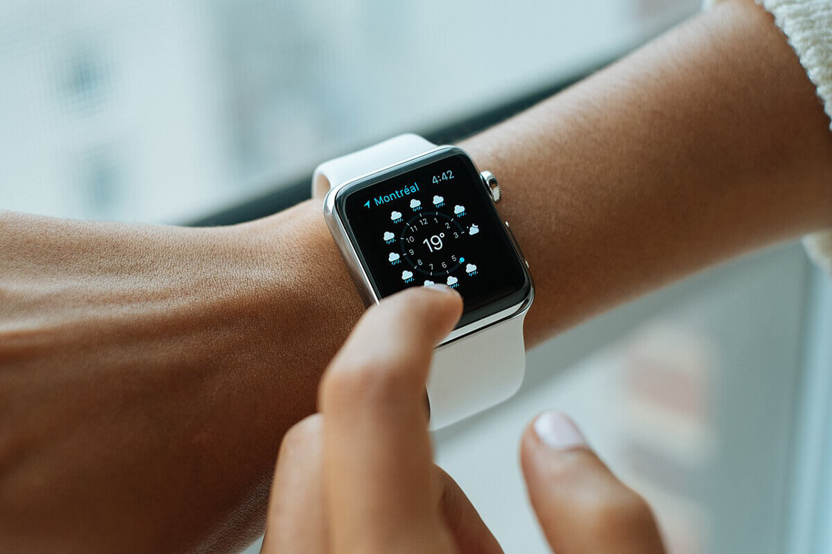 A hand is pressing the screen of a smart watch
